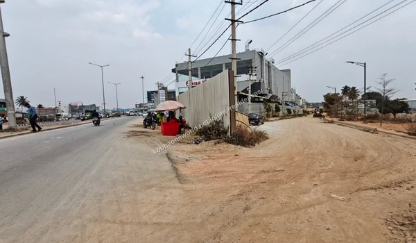 Street perspective showing the dirt pathway and future site entrance located adjacent to the Empire restaurant near Sobha One Residences