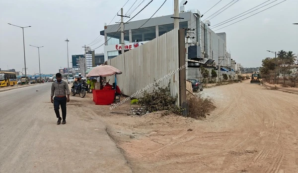 An auto rickshaw navigating the busy street in front of the commercial establishments neighboring Sobha One Residences