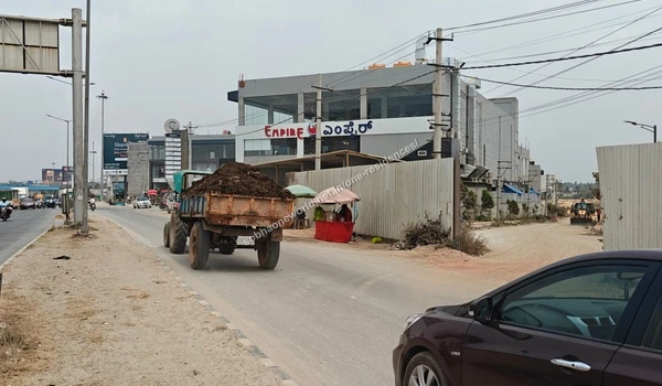 A commuter on a motorcycle passing by the wide street access leading to the under-construction Sobha One Residences site
