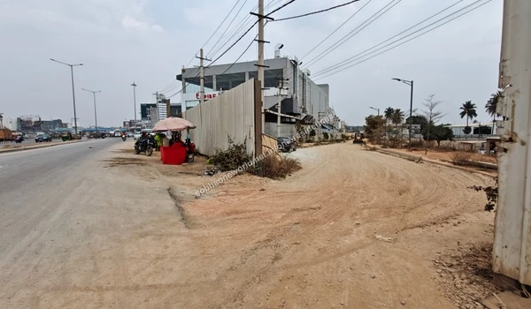 The unpaved access road branching off the main transit corridor leading towards the Sobha One Residences construction grounds