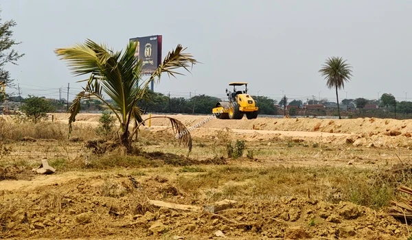 Focus on the disturbed, rocky soil at the Sobha One World property edge with ongoing terrain leveling visible further down the tract.