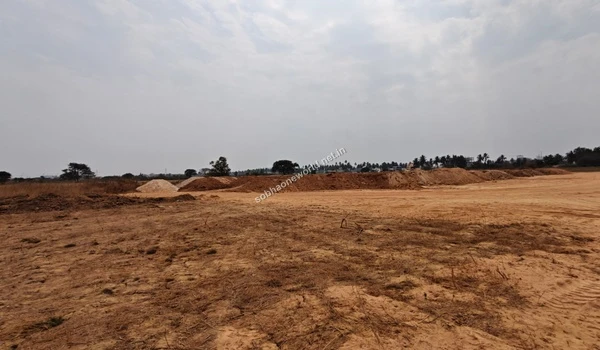 View of the flattened, cleared earth at the Sobha One World site, with a long ridge of soil piles and the distant city skyline visible on the horizon.