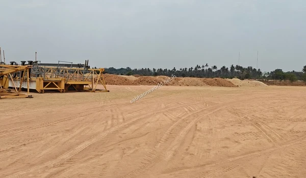 View of construction machinery and structural elements stationed on the leveled ground at the Sobha One World project site, with soil mounds in the background.