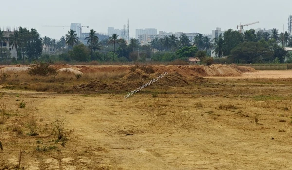 A massive stretch of excavated red earth forming a long boundary line across the heavily graded Sobha One World construction lands.
