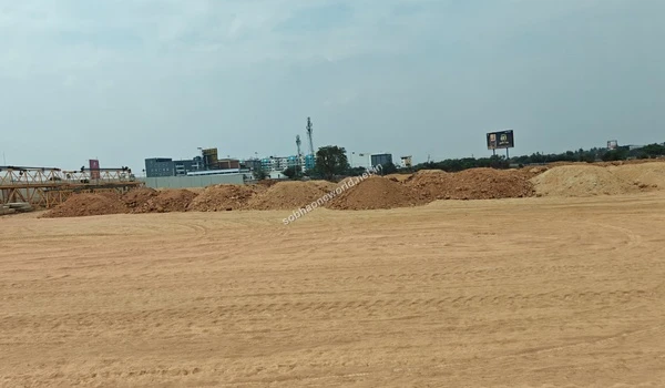 A line of various excavated earth materials and soil collected during the Sobha One World site grading process bordering the main path.