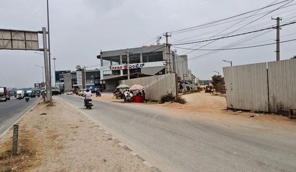 Wide view of the main approach road leading towards the Sobha One World vicinity, showing nearby commercial establishments.