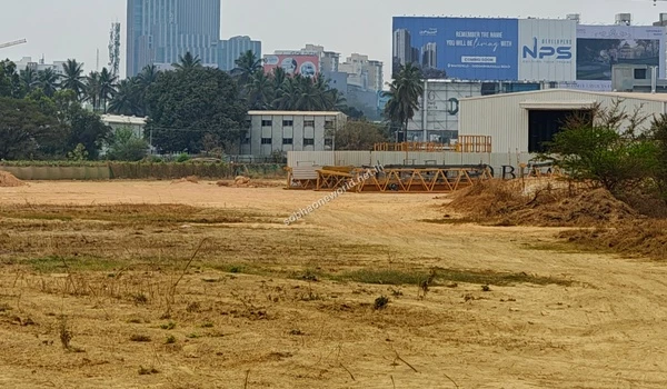 The main construction staging grounds at Sobha One World showing leveled earth, site offices, and large billboards.