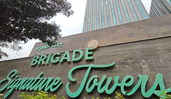 Low angle view of the modern commercial tower facade seen through trees highlighting premium business spaces near Sobha One World