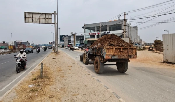 The unpaved perimeter pathway running alongside the main road bordering the Sobha One World upcoming development.