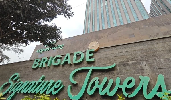 Upward perspective of a premium office building exterior showcasing the thriving corporate neighborhood surrounding the Sobha One World location