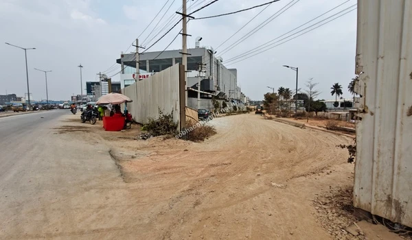 The cleared land and preparatory groundwork visible at the entrance juncture of the Sobha One World luxury complex.