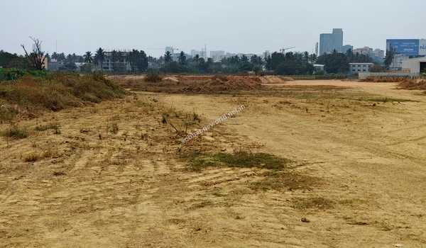 View across the dry brush and graded dirt areas of the Sobha One World property looking towards the distant urban skyline and project staging areas.