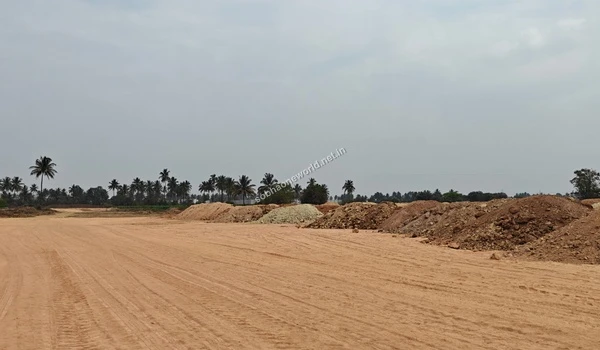 Wide angle view of the expansive Sobha One World construction site showing leveled ground and large piles of excavated red soil under a cloudy sky.