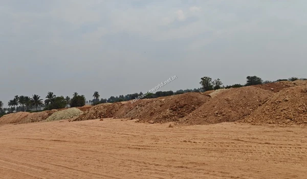Wide landscape shot emphasizing heavy tire tracks leading across the cleared ground towards large soil berms at the Sobha One World development site.