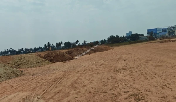 Sweeping view of a wide dirt trail heavily marked by construction activity at Sobha One World, passing alongside long mounds of excavated soil.