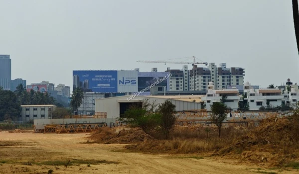 The developing Sobha One World property shown against a backdrop of modern high-rise apartments and large advertising structures in the city.